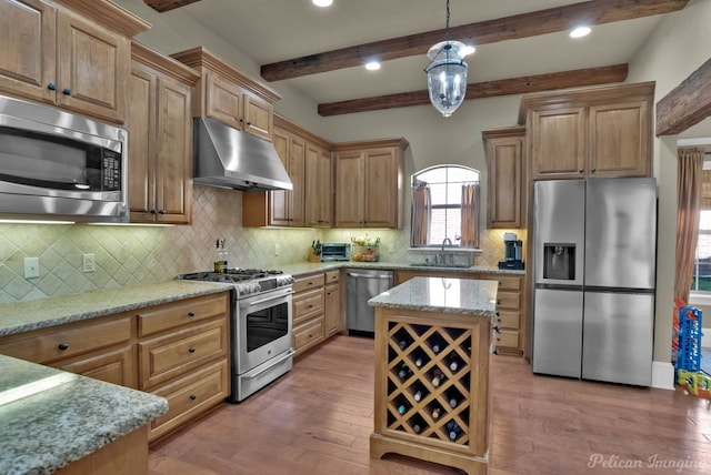kitchen featuring stainless steel appliances, wood finished floors, under cabinet range hood, and a sink