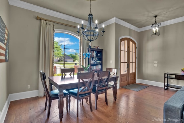 dining area featuring arched walkways, an inviting chandelier, wood-type flooring, baseboards, and ornamental molding