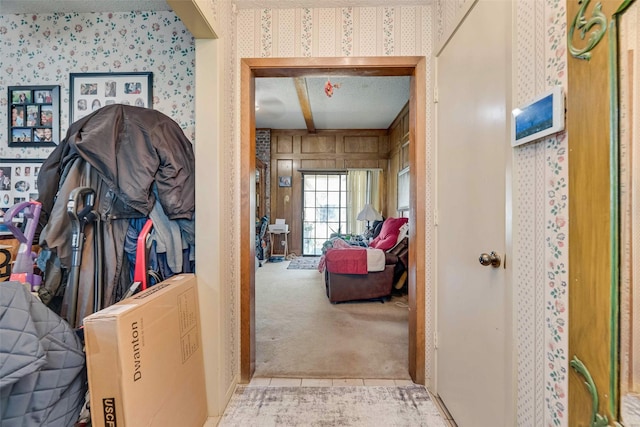 hall with a textured ceiling, wallpapered walls, and carpet
