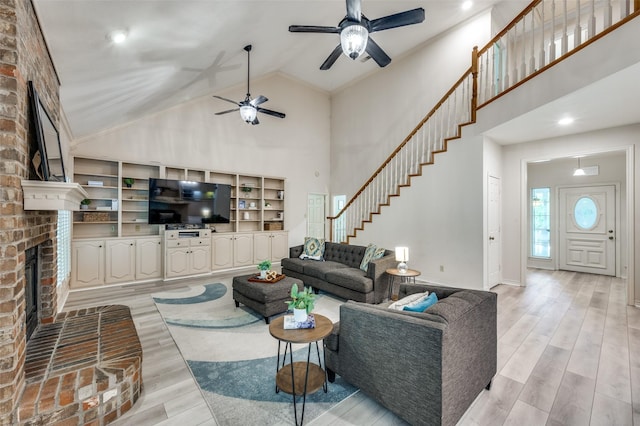 300 Dove Crk, Mckinney, TX 75071 - living area featuring a brick fireplace, ceiling fan, high vaulted ceiling, stairway, and light wood-style flooring