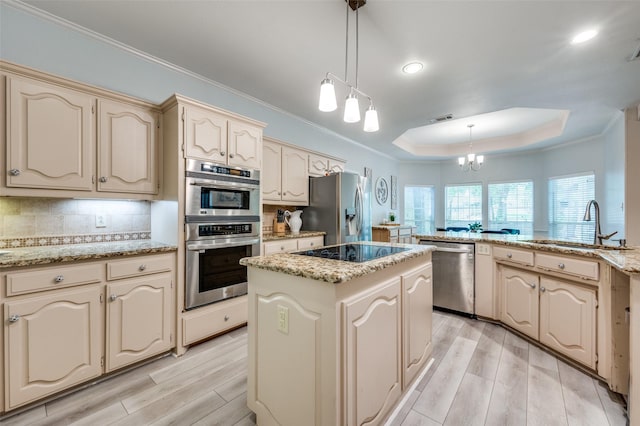 300 Dove Crk, Mckinney, TX 75071 - kitchen with light wood-style floors, a center island, a tray ceiling, cream cabinets, and appliances with stainless steel finishes