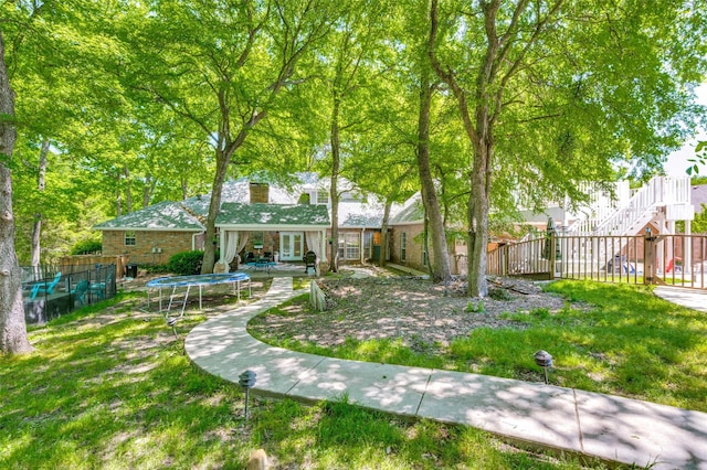 300 Dove Crk, Mckinney, TX 75071 - view of yard featuring fence, a trampoline, french doors, and stairway