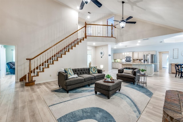 300 Dove Crk, Mckinney, TX 75071 - living room featuring stairs, a ceiling fan, high vaulted ceiling, and light wood-type flooring