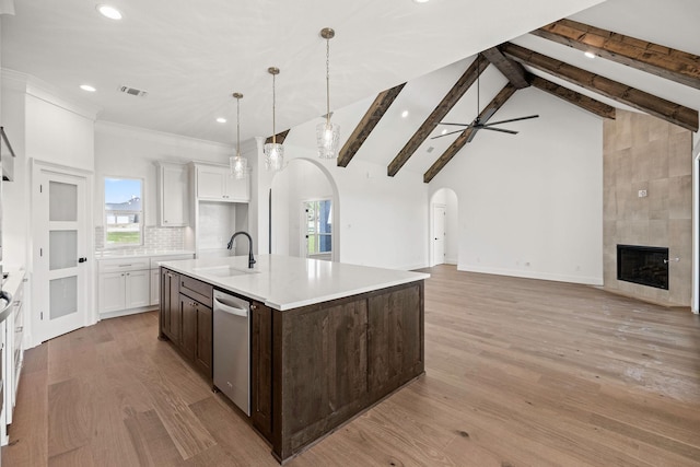 737 Burr Oak Ln, Weatherford, TX 76085 - kitchen with stainless steel dishwasher, a sink, arched walkways, dark brown cabinetry, and visible vents