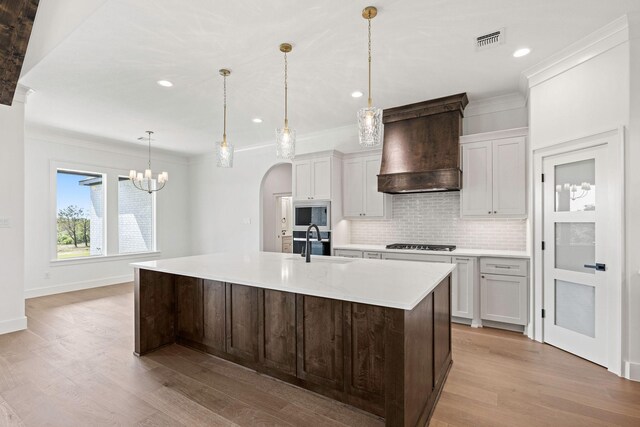 737 Burr Oak Ln, Weatherford, TX 76085 - kitchen featuring arched walkways, built in microwave, visible vents, custom exhaust hood, and backsplash