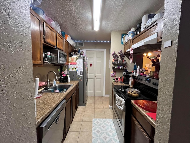 kitchen featuring stainless steel appliances, a sink, a textured ceiling, visible vents, and light tile patterned floors