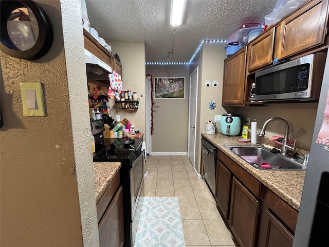 kitchen featuring electric stove, a sink, light tile patterned floors, dishwasher, and stainless steel microwave