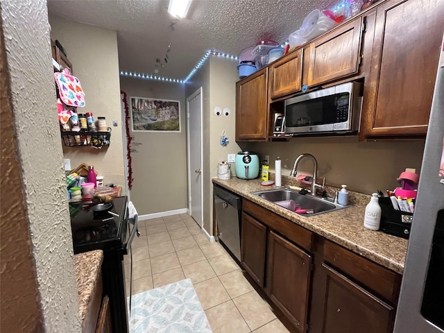 kitchen with light countertops, light tile patterned floors, a sink, a textured ceiling, and appliances with stainless steel finishes