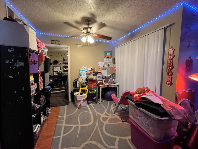 playroom with ceiling fan and a textured ceiling