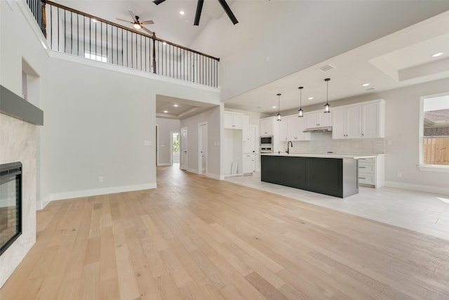 unfurnished living room featuring ceiling fan, a sink, light wood-style flooring, and a fireplace
