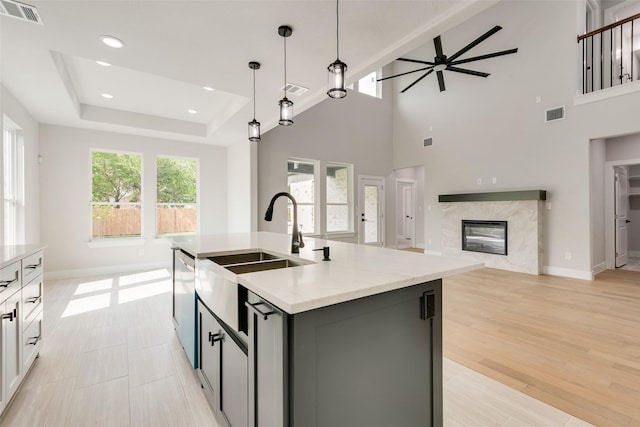 kitchen with visible vents, a sink, a fireplace, a ceiling fan, and decorative light fixtures