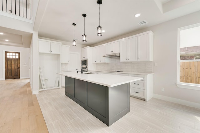 6810 Windward View Dr, Rowlett, TX 75088 - kitchen with under cabinet range hood, tasteful backsplash, white cabinets, light countertops, and recessed lighting