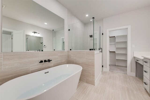 full bathroom featuring a freestanding tub, vanity, a stall shower, and a spacious closet