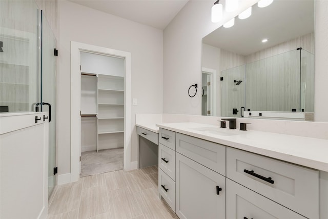 bathroom with vanity, baseboards, a stall shower, and a spacious closet