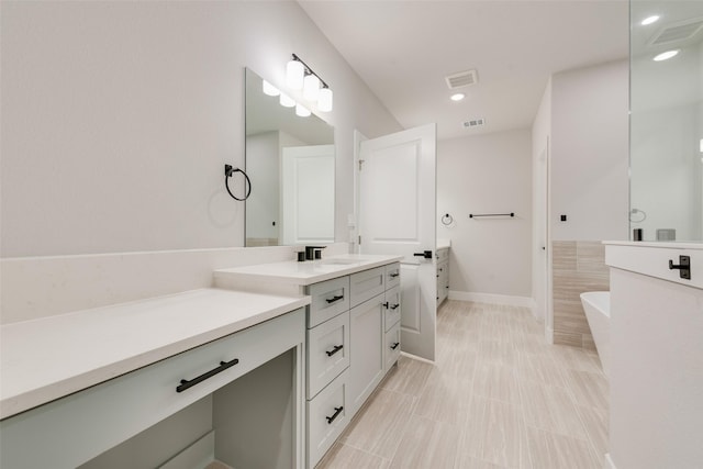 bathroom with vanity, a freestanding tub, and visible vents