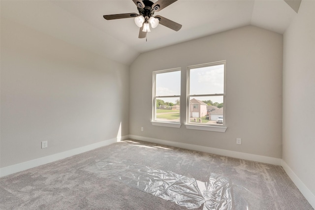 carpeted spare room featuring baseboards, ceiling fan, and vaulted ceiling