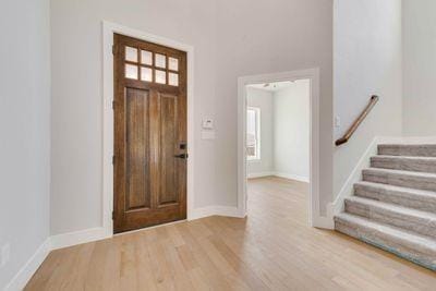 foyer entrance with baseboards, wood finished floors, and stairway