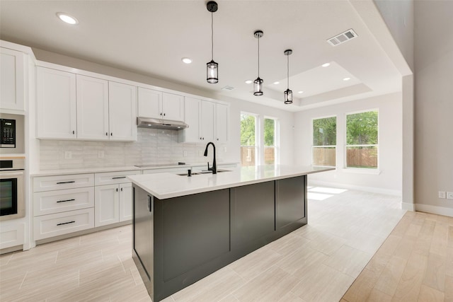 kitchen featuring visible vents, stainless steel oven, black electric stovetop, under cabinet range hood, and tasteful backsplash