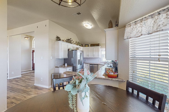 231 Dove Hill Ln, Weatherford, TX 76088 - dining area with light wood finished floors, a textured ceiling, baseboards, visible vents, and lofted ceiling