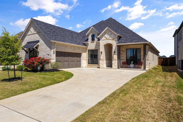 french provincial home with a garage, driveway, stone siding, and a front yard