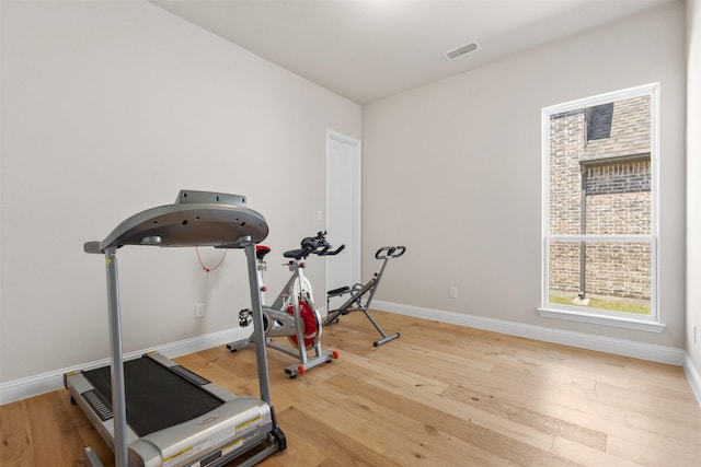 exercise room featuring wood finished floors, visible vents, and baseboards