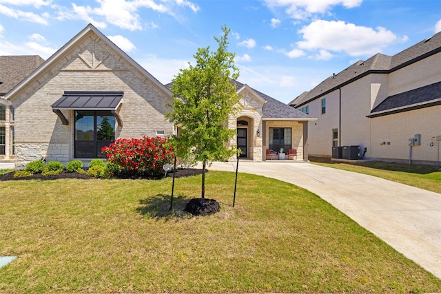 french country inspired facade featuring cooling unit, driveway, stone siding, brick siding, and a front yard