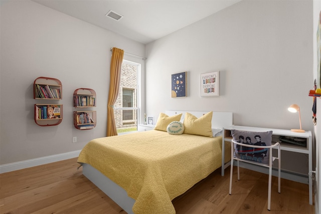 bedroom featuring baseboards, wood finished floors, and visible vents