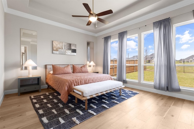 bedroom featuring a raised ceiling, light wood-style flooring, crown molding, and multiple windows