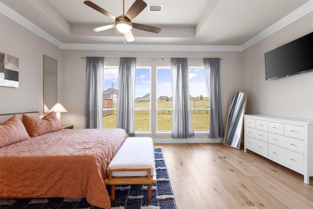 bedroom with multiple windows, a tray ceiling, and visible vents