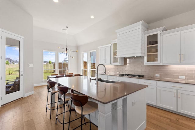 kitchen with stainless steel gas stovetop, light wood-type flooring, decorative backsplash, and a sink