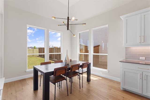 dining space featuring baseboards, an inviting chandelier, and light wood-style floors