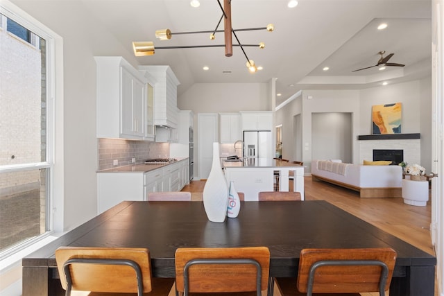 dining room featuring light wood-type flooring, plenty of natural light, a fireplace, and recessed lighting