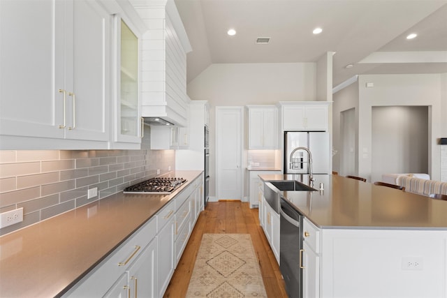 kitchen featuring an island with sink, light wood-style flooring, white cabinets, appliances with stainless steel finishes, and visible vents