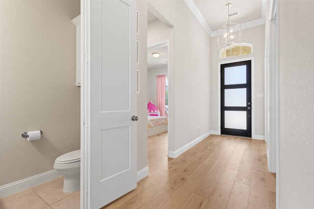 entrance foyer with light wood finished floors, baseboards, visible vents, a chandelier, and ornamental molding