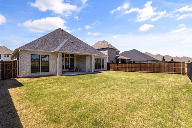 rear view of house with brick siding, a yard, a patio, and a fenced backyard