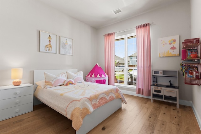 bedroom with baseboards, wood finished floors, and visible vents