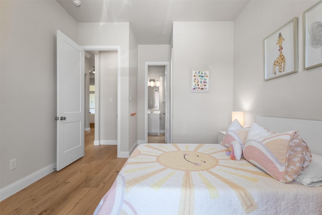 bedroom with light wood-style floors, ensuite bath, and baseboards