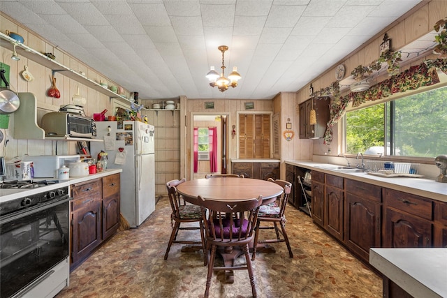 kitchen featuring light countertops, white appliances, a sink, and a notable chandelier
