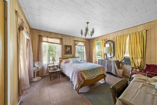 bedroom with brick patterned floor, a notable chandelier, and wooden walls