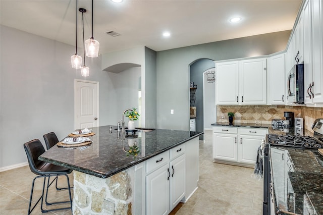 5220 Grove Cove Dr, Mckinney, TX 75071 - kitchen featuring a sink, arched walkways, white cabinets, backsplash, and appliances with stainless steel finishes