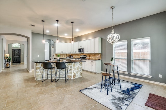 5220 Grove Cove Dr, Mckinney, TX 75071 - kitchen featuring dark countertops, decorative backsplash, arched walkways, appliances with stainless steel finishes, and visible vents