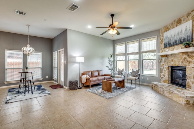 5220 Grove Cove Dr, Mckinney, TX 75071 - tiled living room with baseboards, a stone fireplace, visible vents, and ceiling fan with notable chandelier