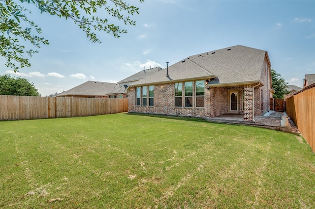 5220 Grove Cove Dr, Mckinney, TX 75071 - back of property with roof with shingles, a fenced backyard, brick siding, a lawn, and a patio