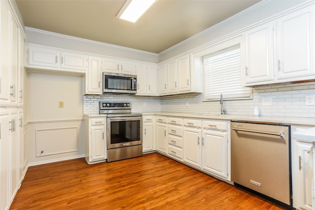 1 Roaring Creek Ct, Trophy Club, TX 76262 - kitchen featuring white cabinets, a sink, wood finished floors, light countertops, and appliances with stainless steel finishes