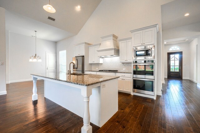996 Heather Falls Dr, Rockwall, TX 75087 - kitchen with premium range hood, high vaulted ceiling, stainless steel appliances, a center island with sink, and dark wood finished floors