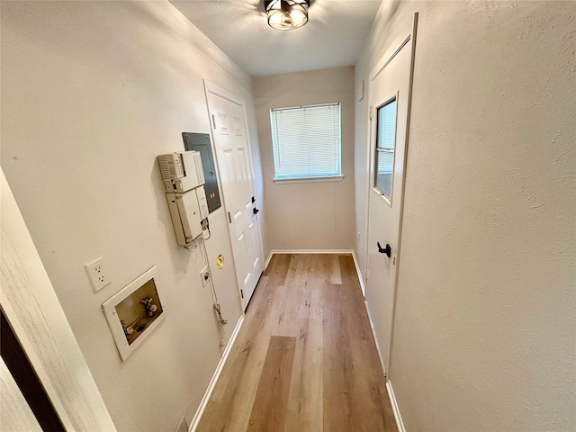 hallway featuring light wood finished floors and baseboards