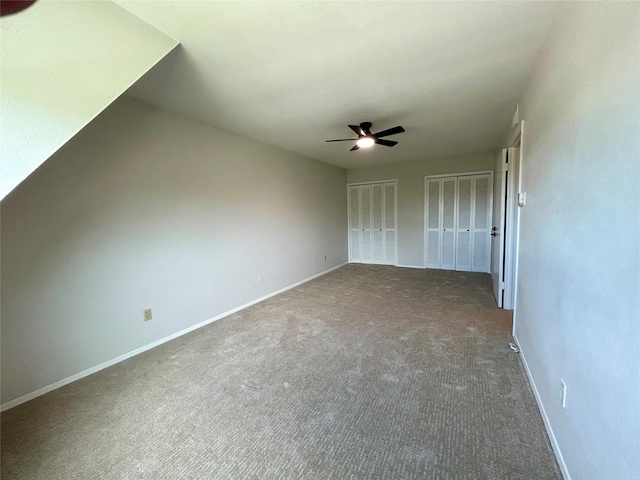 unfurnished bedroom with ceiling fan, baseboards, multiple closets, and carpet