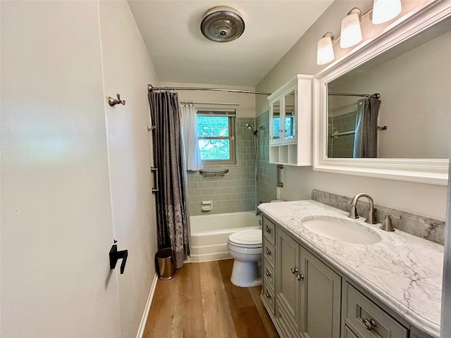 full bathroom featuring wood finished floors, toilet, vanity, baseboards, and shower / bath combo