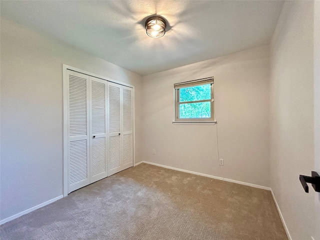 unfurnished bedroom featuring baseboards, carpet flooring, and a closet