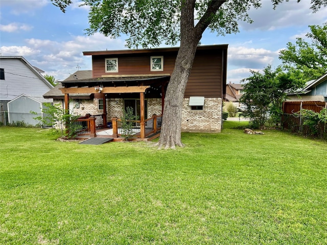 rear view of property featuring brick siding, a yard, a patio, and fence